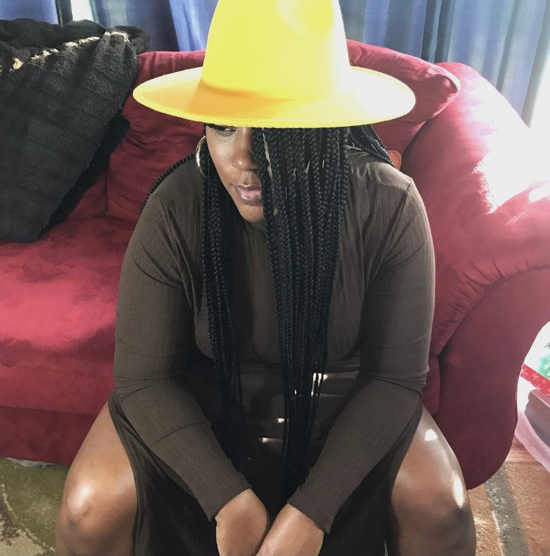 Beautiful woman with a mustard color fedora hat and a Brown turtleneck dress with slits on both sides 