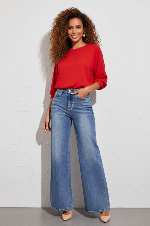A woman with pair of high waist wide leg jeans with a bell bottom style, featuring a washed-out denim color and a button up front.

